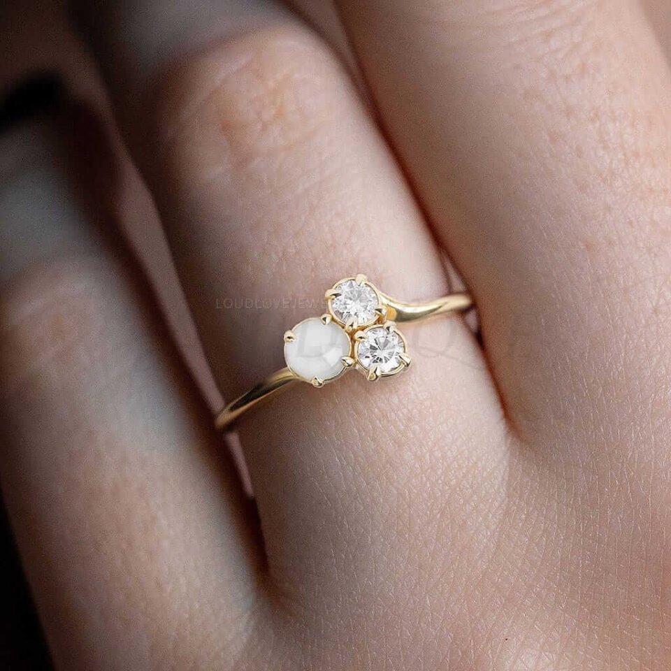 Gold ring with akoya pearl and moissanite cluster styled as a modern asymmetrical piece.