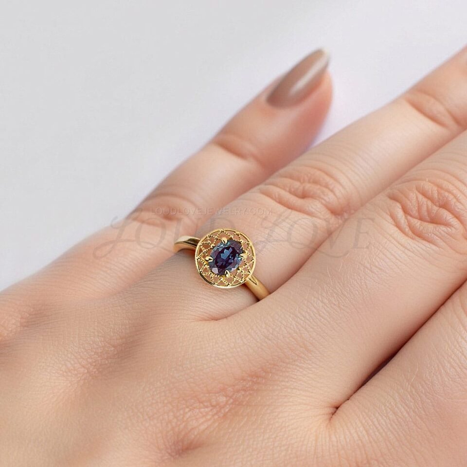 Yellow gold ring with oval alexandrite and milgrain detailing styled on hand.