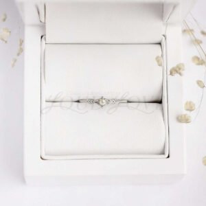 Tiny pearl ring with silver arrow motif band shown in a soft display case.