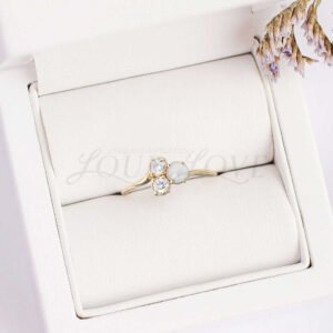 Three-stone pearl and moissanite ring arranged in a soft cushioned display holder.