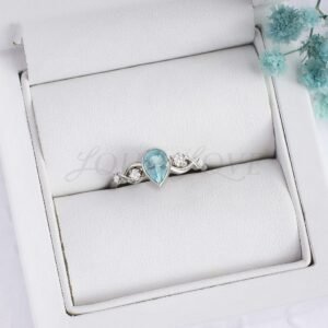 Aquamarine ring with 4 side stones and textured band shown in a soft display box.