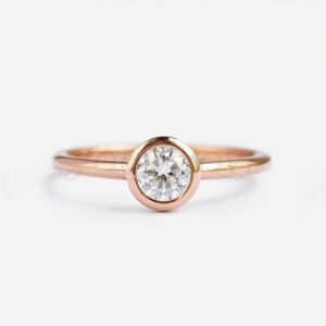 Classic bezel set round moissanite engagement ring with rose gold band.