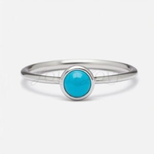 Front angle of solitaire ring with turquoise cabochon set in a smooth silver bezel mount.