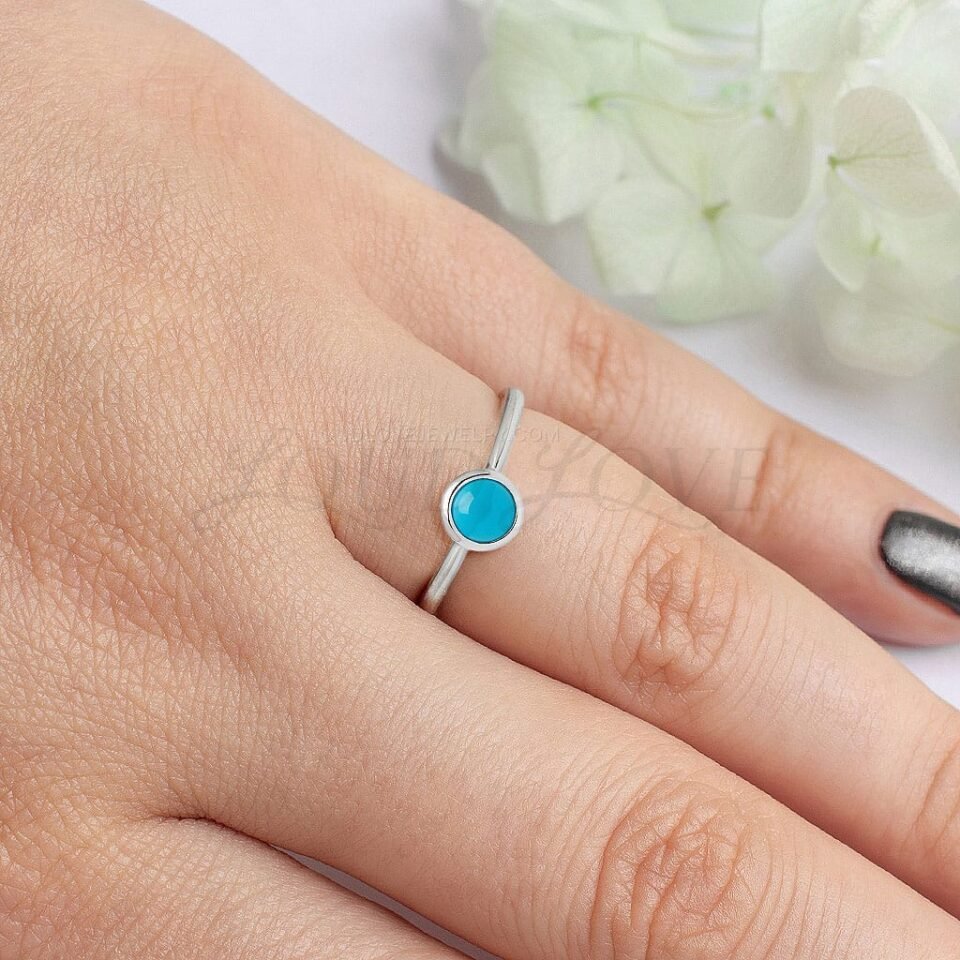 Turquoise cabochon solitaire ring with bezel setting in silver, styled on hand for a natural look.