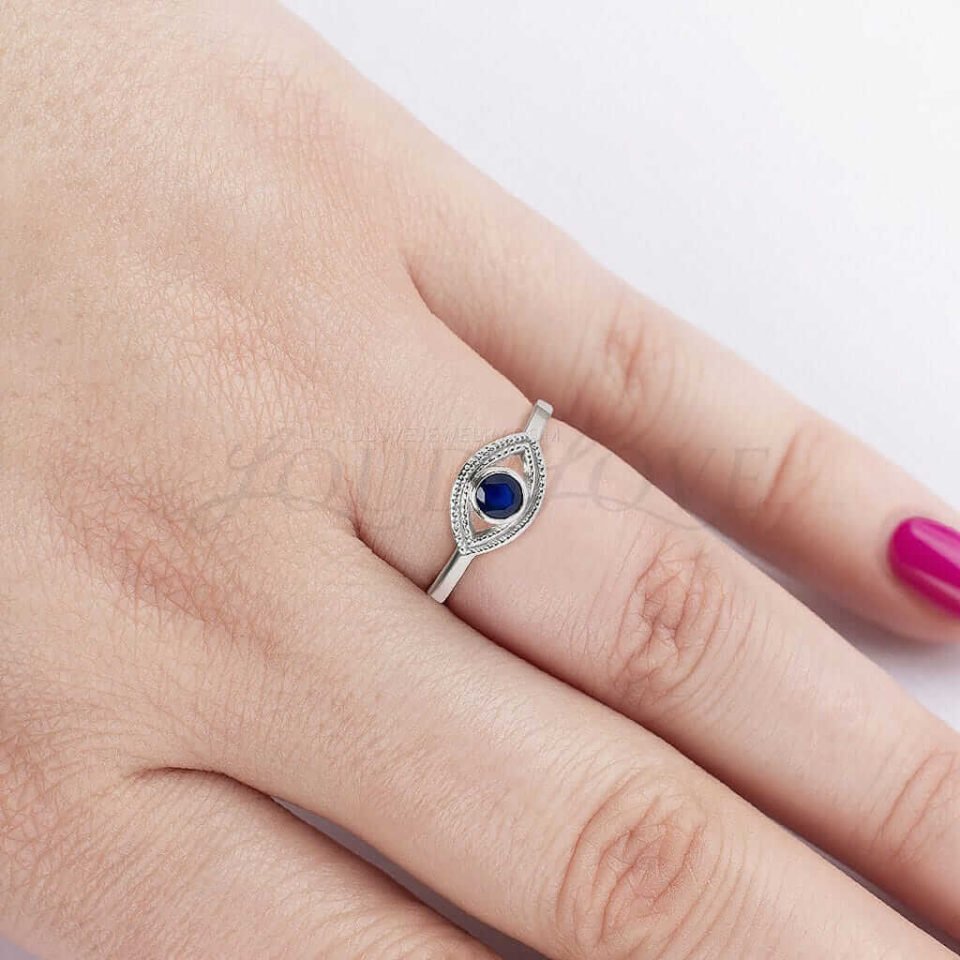 Evil eye design ring with lab sapphire styled on hand as a symbolic accessory.