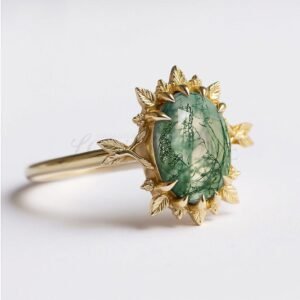 Oval moss agate ring with leaf halo worn as a statement botanical-style piece.