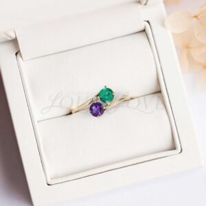 Two-stone bypass ring with round amethyst and emerald, plus accent stones.