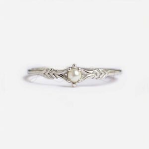 Small round pearl on a textured silver band with delicate arrow design.