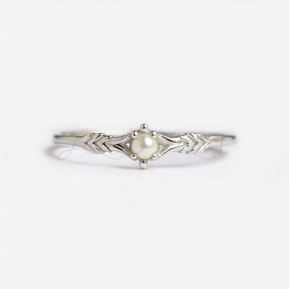 Small round pearl on a textured silver band with delicate arrow design.