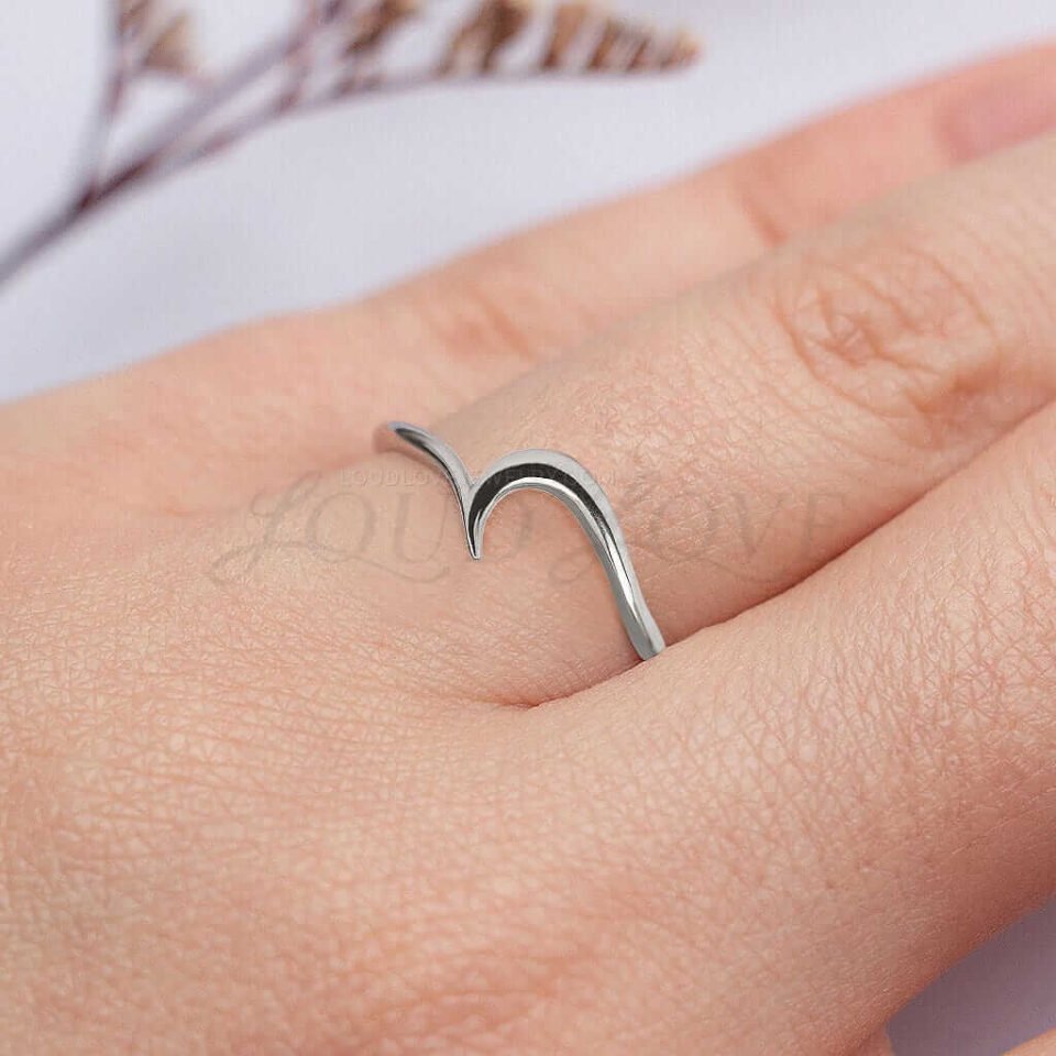 Contoured silver ring with wave design, styled as modern minimalist jewelry.