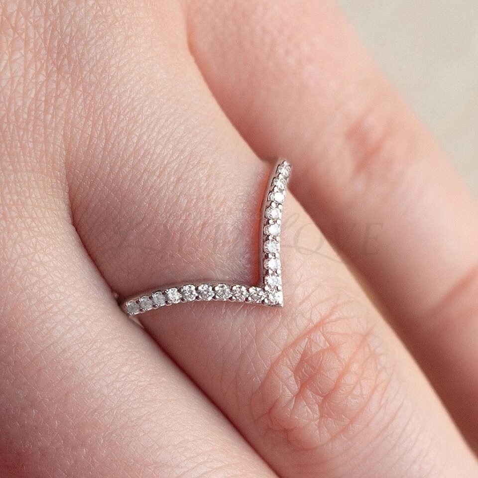Elegant chevron eternity ring with round diamonds in pave setting, worn on hand.