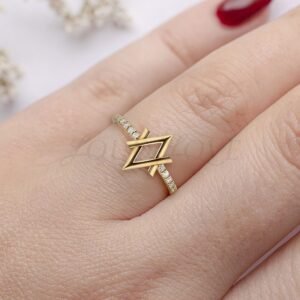 Geometric lozenge-shaped ring in gold with pavé diamonds, worn for a bold modern look.