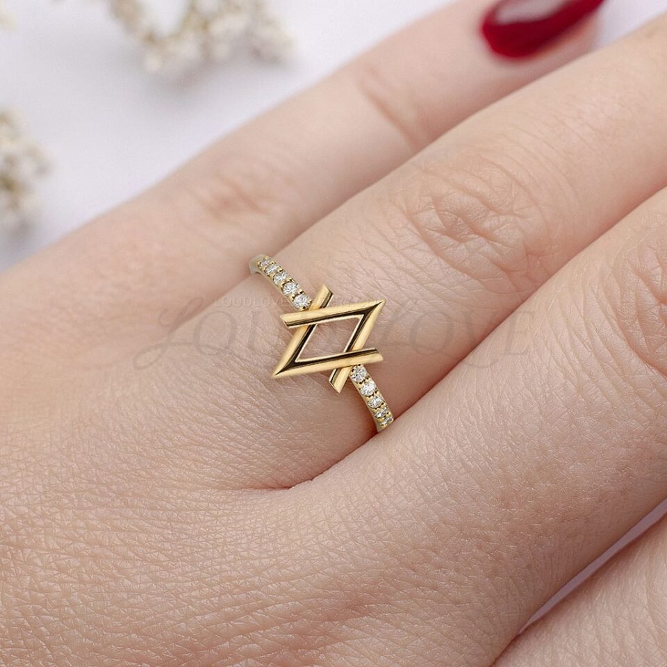 Geometric lozenge-shaped ring in gold with pavé diamonds, worn for a bold modern look.