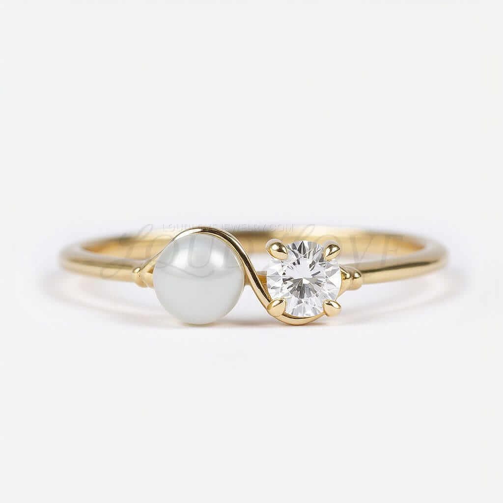 Two-stone engagement ring with cultured pearl and lab diamond joined by a thing gold wave.