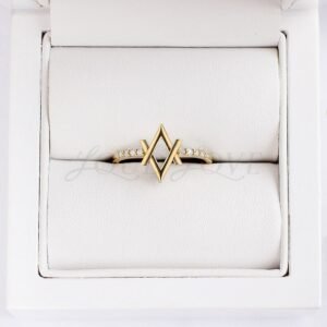 Contemporary gold ring with double V silhouette and pavé diamonds in jewelry packaging.