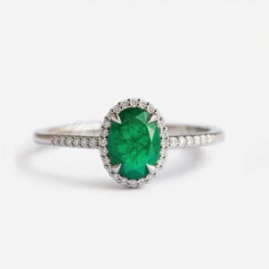 Oval lab-grown emerald with side stone halo and half eternity band in white gold.
