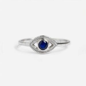 Silver evil eye ring with round lab-grown blue sapphire at the center.