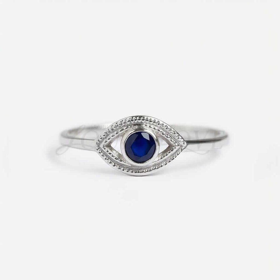 Silver evil eye ring with round lab-grown blue sapphire at the center.