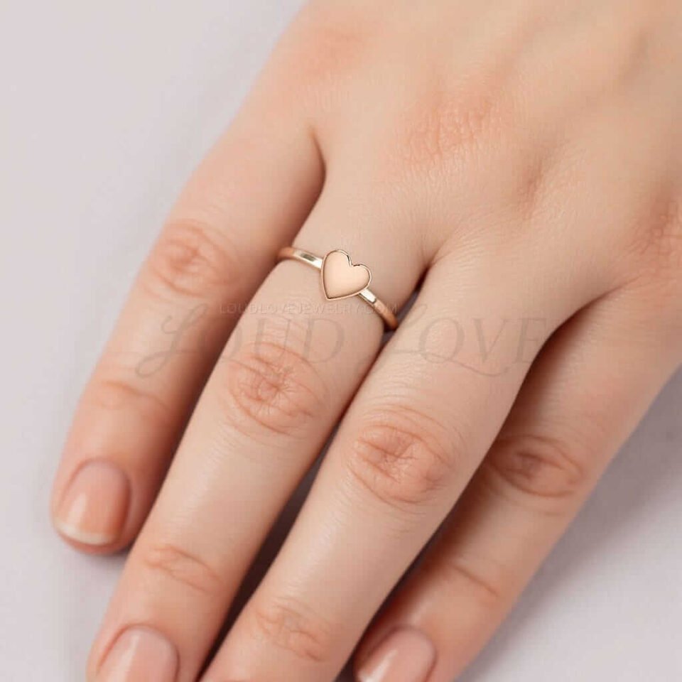 Female hands featuring a 14k rose gold ring with minimal heart shape.