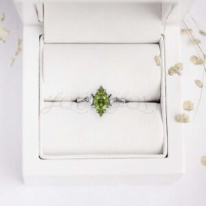 Vibrant green marquise-cut peridot and white accents on a textured band, set on a geometric band.