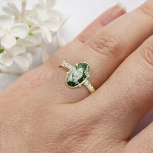 Earthy moss agate ring with gold rim and accent stones worn for a distinctive elegant look.