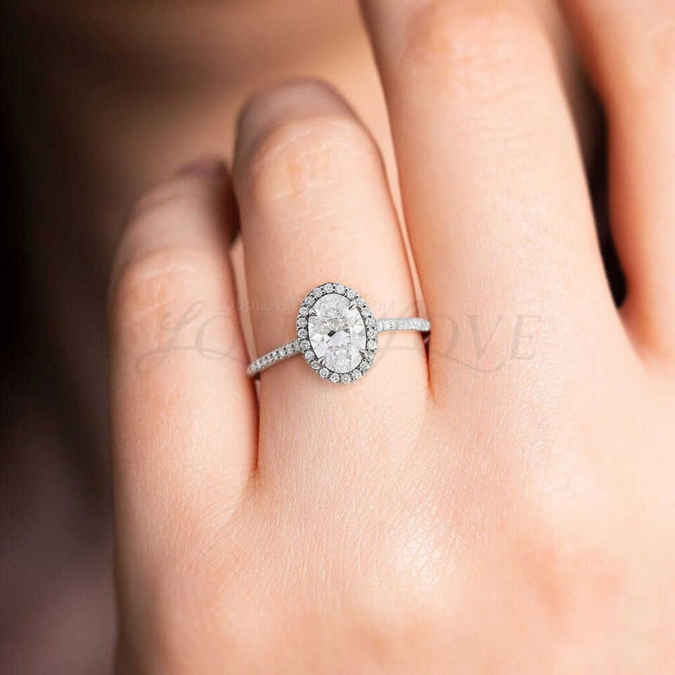 Elegant gold ring with oval moissanite, halo setting, and a diamond-accented band.
