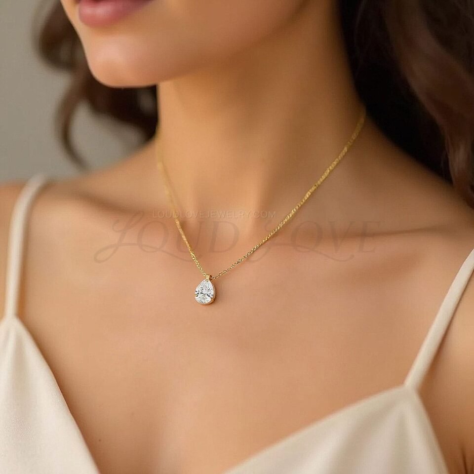 Elegant pear diamond pendant resting at the neckline, showcasing a sleek solitaire design.