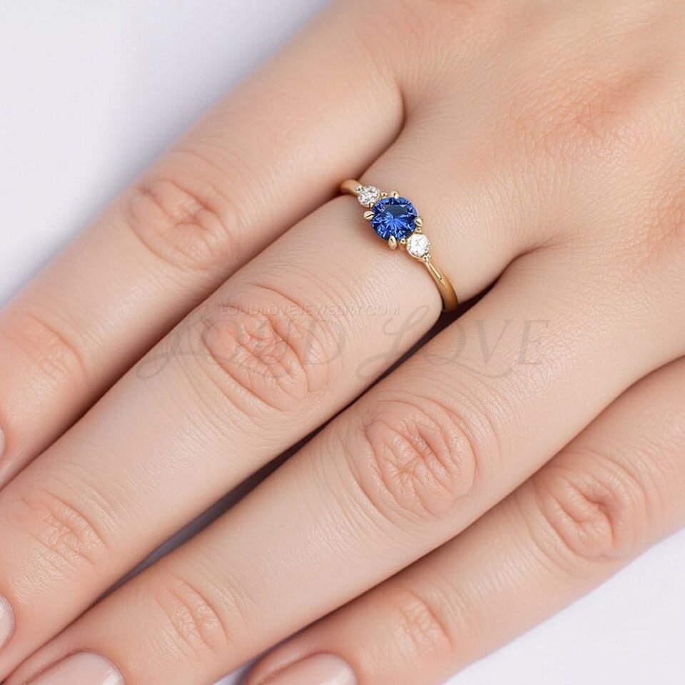 Three-stone ring with blue sapphire center and white side stones styled on hand.