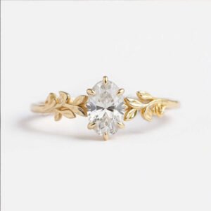 Oval moissanite ring with a detailed leaf band in yellow gold.