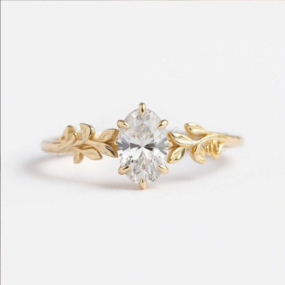 Oval moissanite ring with a detailed leaf band in yellow gold.
