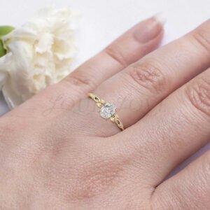 Nature-inspired engagement ring with oval moissanite and yellow gold leaf band worn on hand.