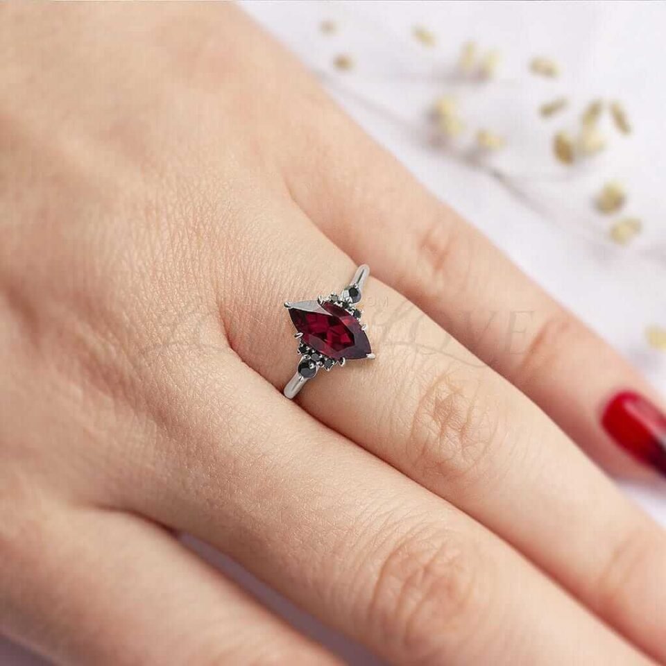 Large marquise garnet flanked by round and marquise black moissanites, styled on a hand.