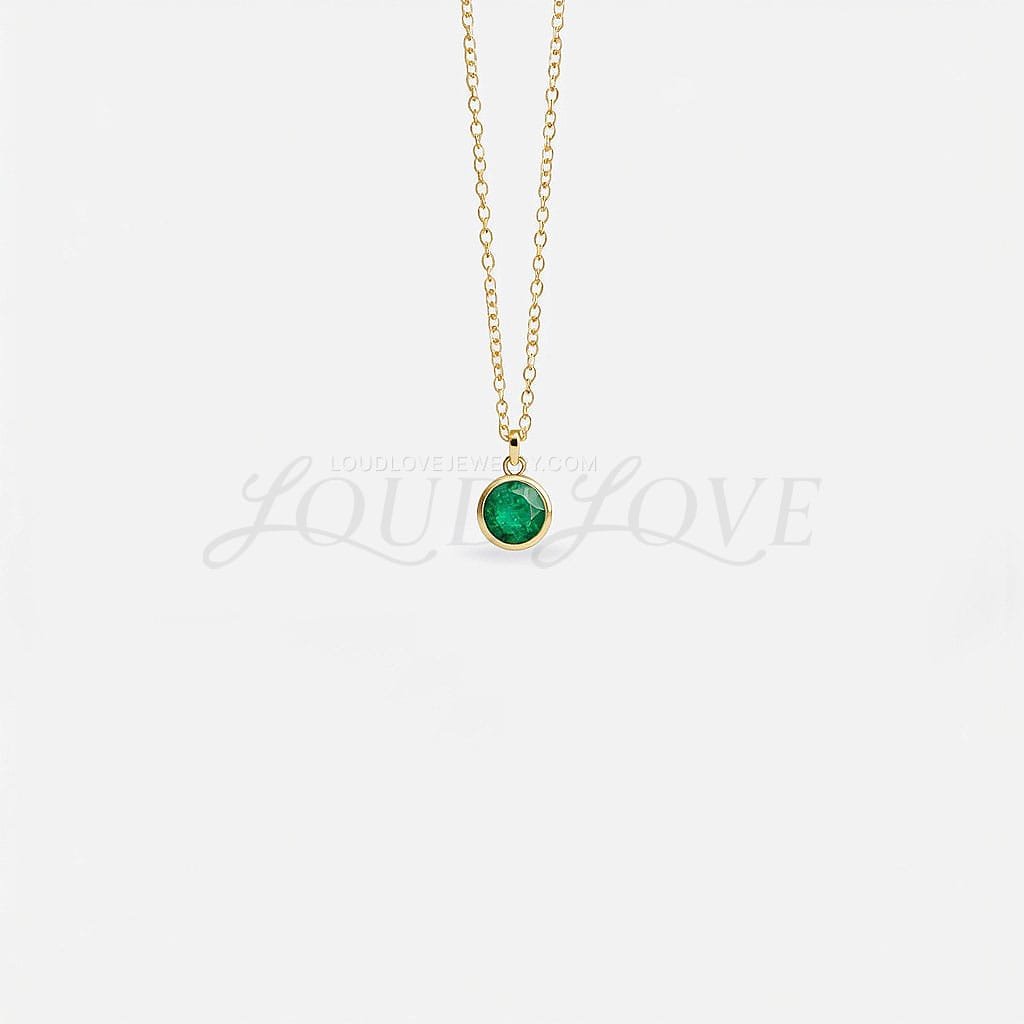 Round emerald in a bezel setting on a fine chain, capturing May's vibrant green birthstone.