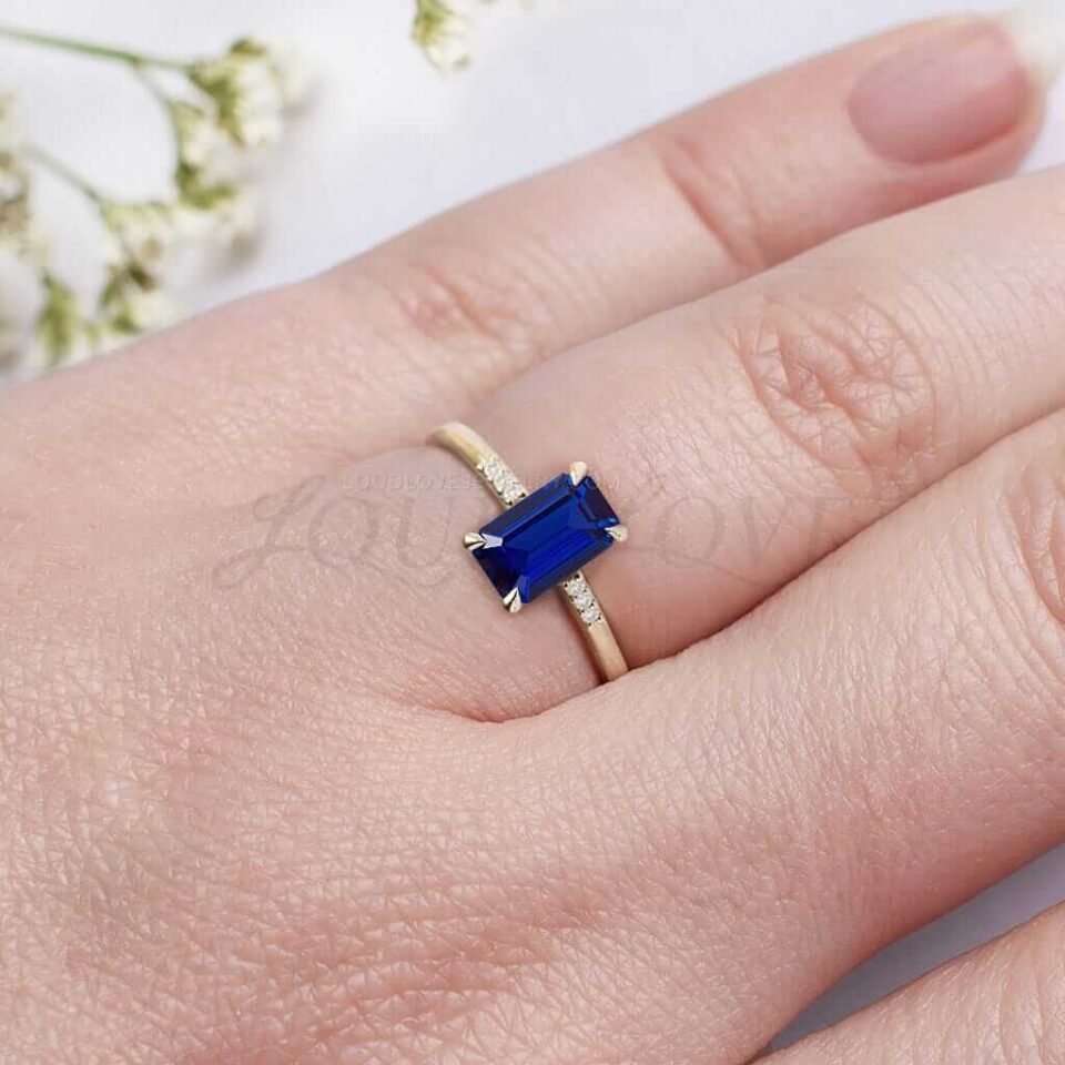 Lab-grown blue sapphire ring with tapered side accents styled as a sustainable engagement piece.