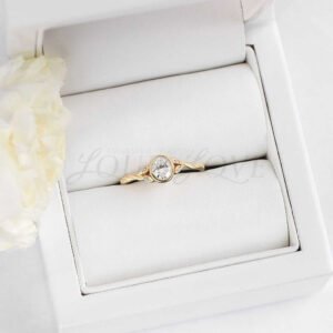 Bezel-set moissanite ring with four-leaf and side stone design.