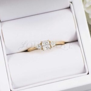 Three-stone princess cut moissanite ring with claw prongs and triangle side stones.