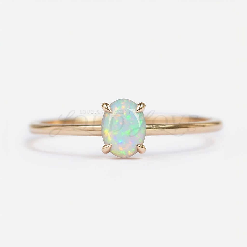 Oval opal solitaire set with claw prongs on a clean gold band, glowing with soft iridescence.