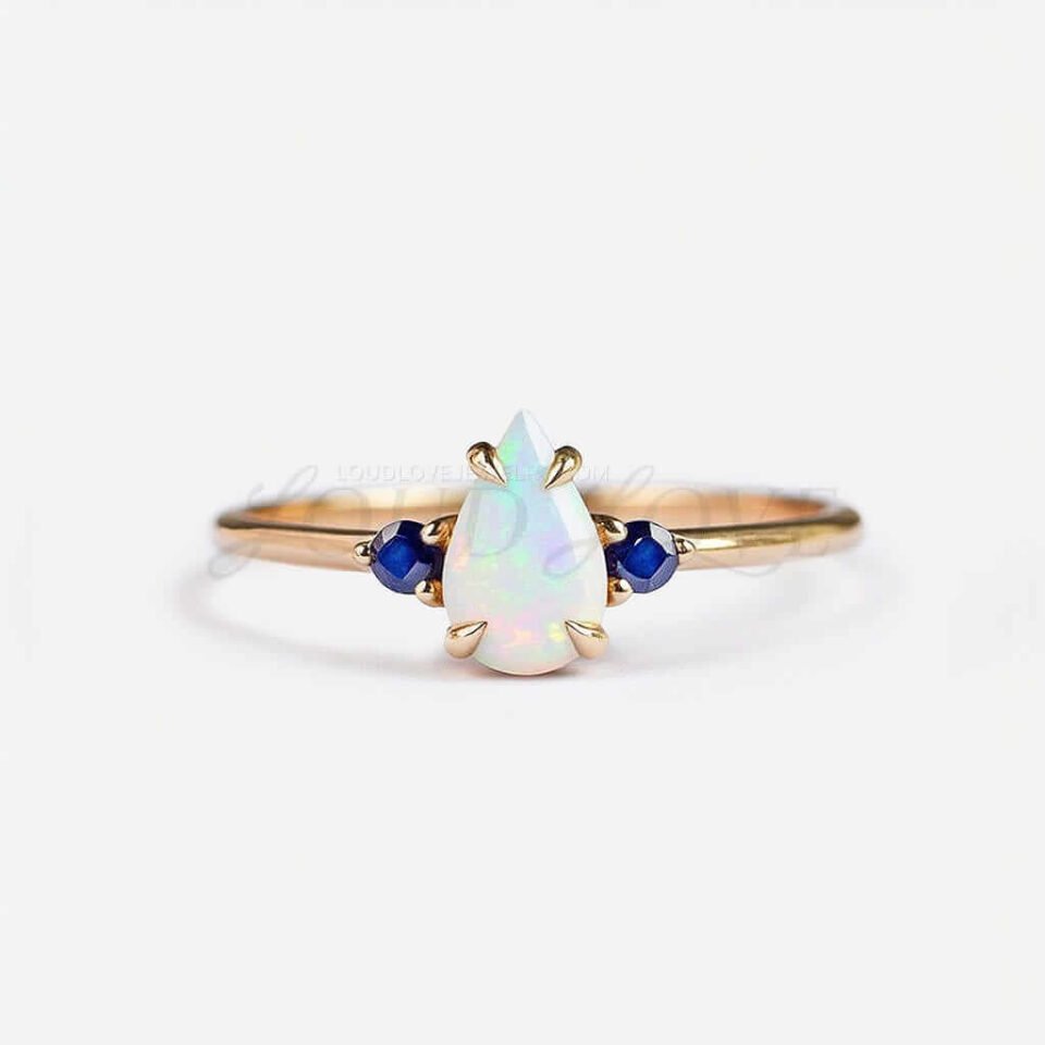 Pear-shaped opal center stone paired with two round sapphires in a classic three-stone arrangement