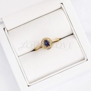 Dreamcatcher-inspired alexandrite ring with gold lace details displayed in a soft holder.
