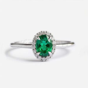Oval lab-grown emerald with a white gold halo setting and a thin polished band.