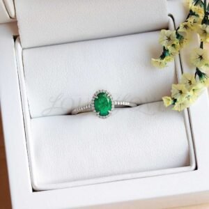 Emerald ring with halo and moissanite half band in a soft presentation holder.