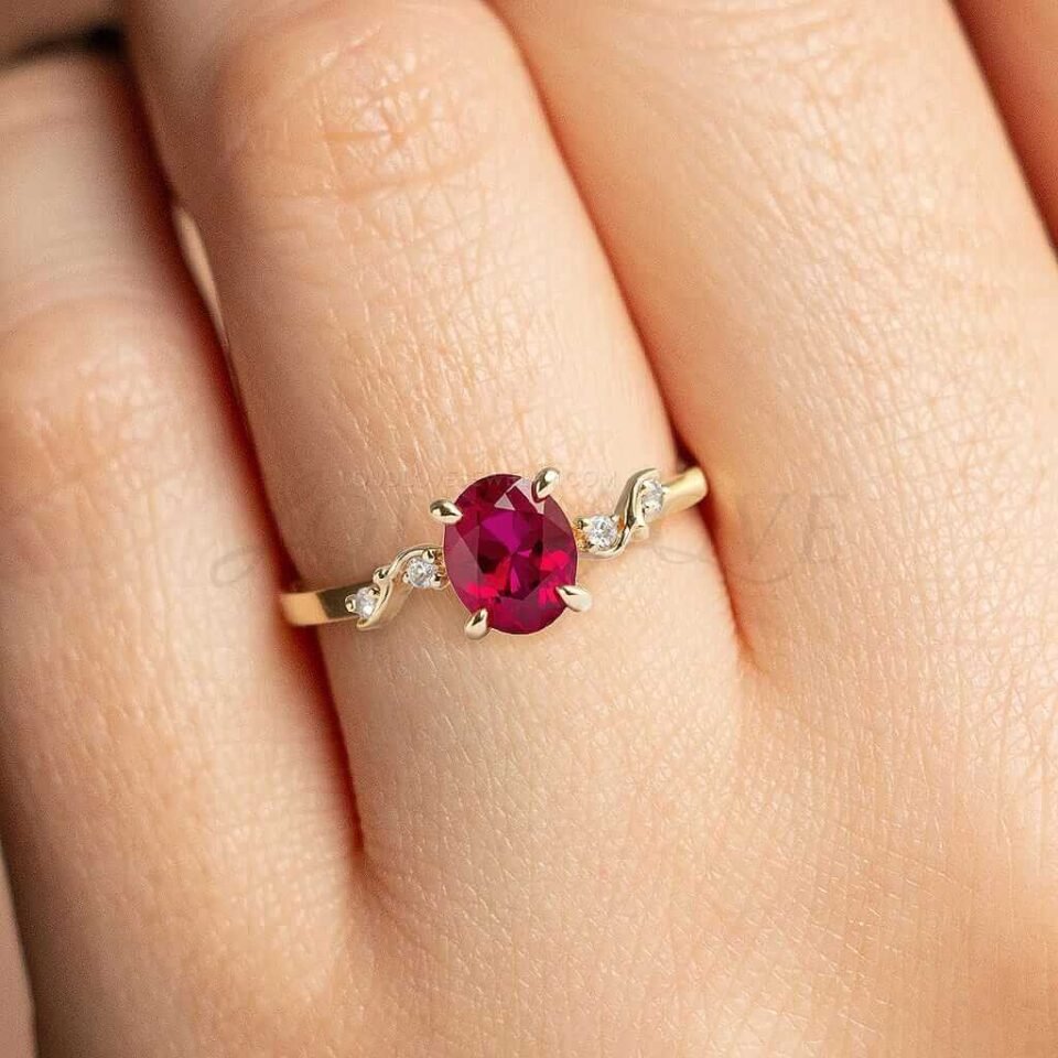 Red lab ruby centerpiece with gold detail and four sparkling side stones.
