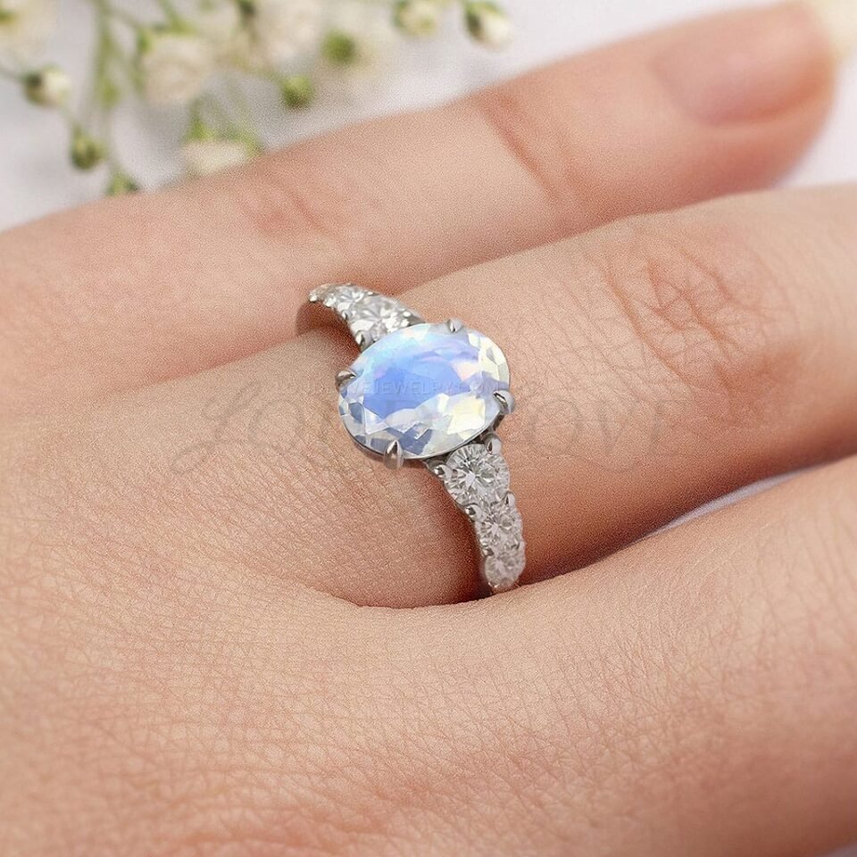 Sterling silver ring with oval moonstone and sparkling side stones worn on hand.