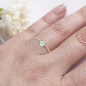 Simple gold ring with oval opal center, worn as a delicate and meaningful promise piece.