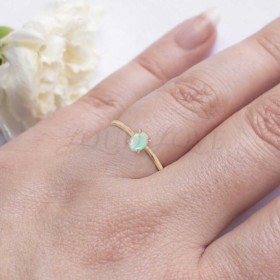 Simple gold ring with oval opal center, worn as a delicate and meaningful promise piece.