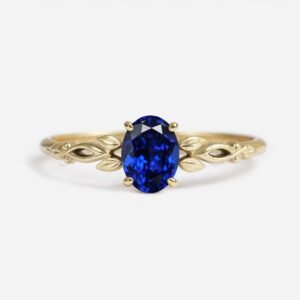Oval lab-grown sapphire solitaire in a floral-inspired gold setting with leaf details.