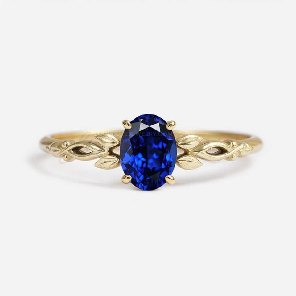Oval lab-grown sapphire solitaire in a floral-inspired gold setting with leaf details.