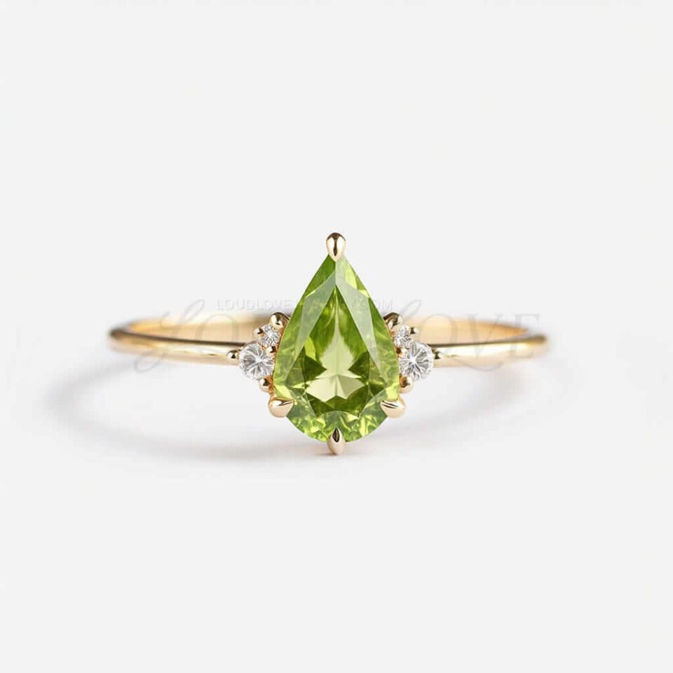 Pear-shaped peridot with four white stones on a fine yellow gold band, elegant and ligh.