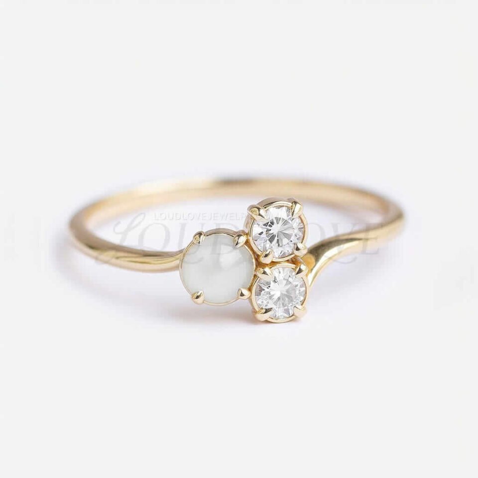 Asymmetrical cluster ring with round akoya pearl and two moissanites on a gold band.