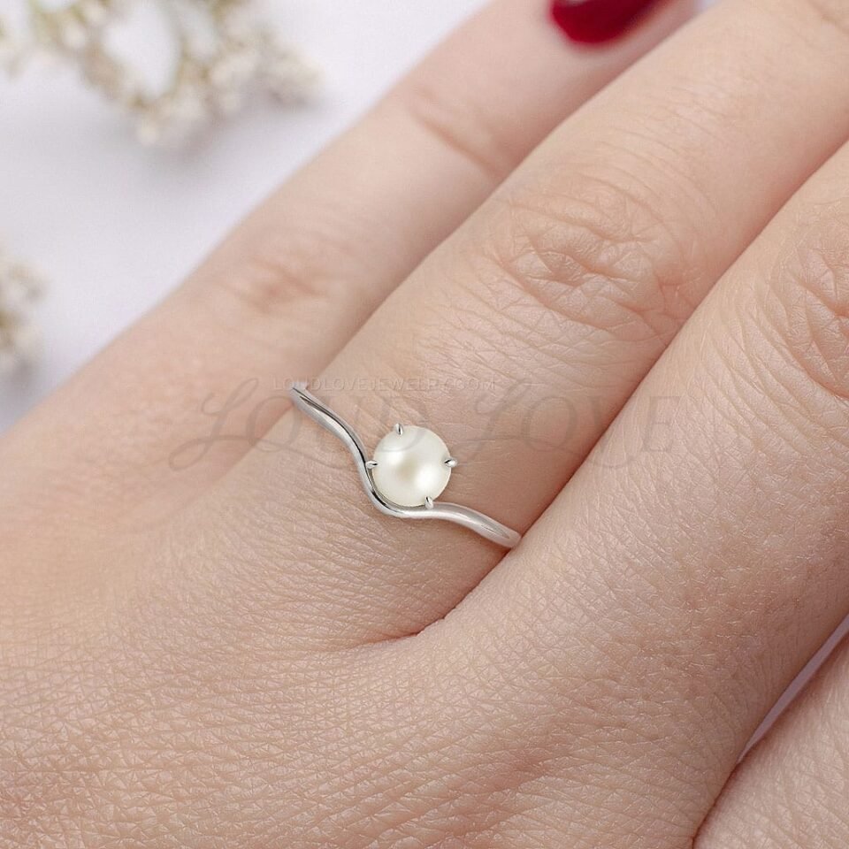 Akoya pearl simple engagement ring on a model's hand, styled in silver.